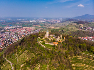 Beautiful top view of the Starkenburg castle in the German city of Heppenheim. The castle is high on the mountain. Mountains and the blue sky in the background. Tiled roofs of houses.