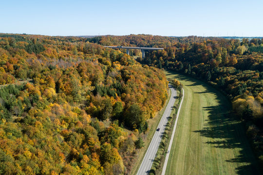 Germany, Baden-Wurttemberg, Heidenheim an der Brenz, Drone view of highway stretching along edge of autumn forest