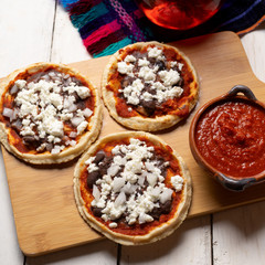 Mexican red sopes with cheese and beans on white background