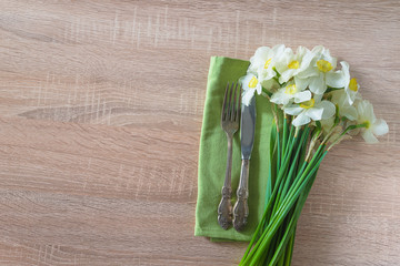 Spring table setting with bouquet of white daffodils. Vintage fork and knife and bouquet of white daffodils on green napkin and