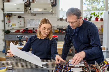 Two electricians working on circuitry in workshop
