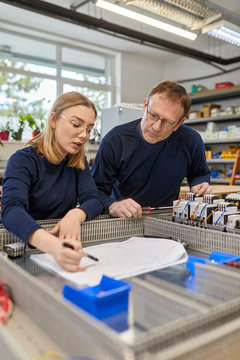 Two electricians working on circuitry in workshop