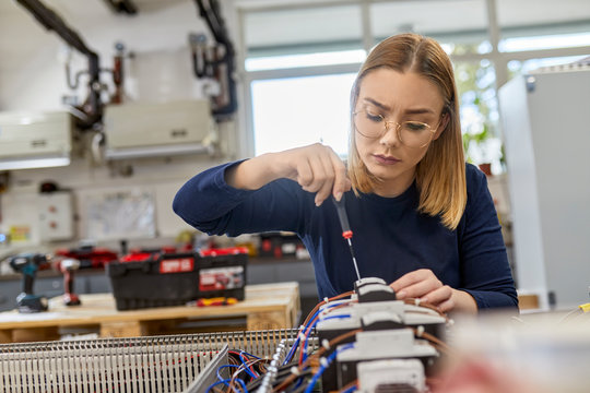 Female electrician working on circuitry in workshop