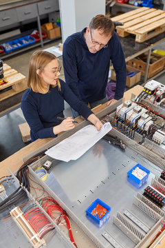Two electricians working on circuitry in workshop