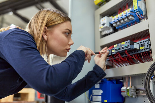 Female electrician working on circuitry in workshop
