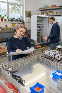 Young woman on the phone in electrical workshop