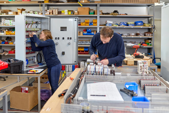 Two electricians working in workshop