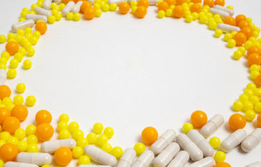 colorful pills for viral diseases in circle frame with copyspace for text. Prevention of influenza, coronavirus, covid-19. yellow, orange vitamins on white background. medical healthcare concept