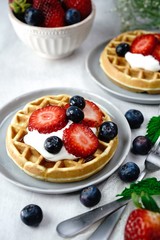 Homemade mini Waffles topped with fresh berries and cream, selective focus