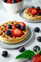 Homemade mini Waffles topped with fresh berries and cream, selective focus