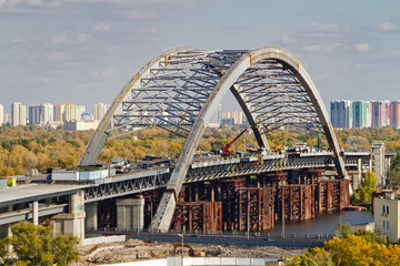 Combined car and subway bridge under construction. Mounting of steel arch. Unfinished Podilskiy bridge (Podilsko-Voskresenskiy bridge). Kiev, Ukraine. Kyiv, Ukraine.