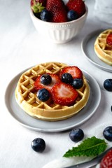 Homemade mini Waffles topped with fresh berries and cream, selective focus