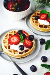 Homemade mini Waffles topped with fresh berries and cream, selective focus