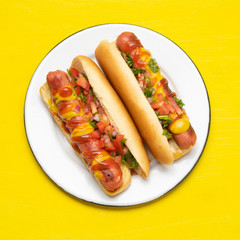 Hot dog with pico de gallo salad on yellow background