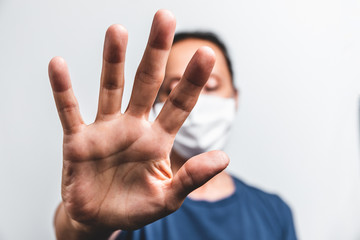 Elderly person wearing a mask to prevent the spread of the coronavirus during the pandemic, making an stop sign.