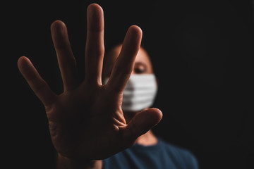 Elderly person wearing a mask to prevent the spread of the coronavirus during the pandemic, making an stop sign.