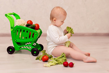 Little girl 10-12 months at home with a cart of vegetables.