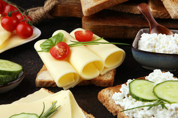 rolled slices of golden gouda cheese or cream cheese on a sandwich garnished with sliced cucumber and herbs. bread or toast with cheese for breakfast