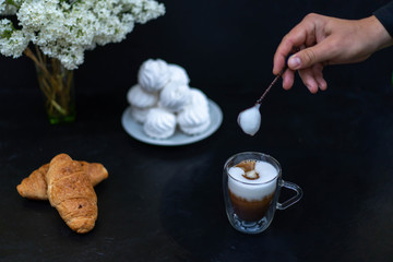Cup of cappuccino with coffee beans and croissant, marshmallow and a bouquet of flowers. B.