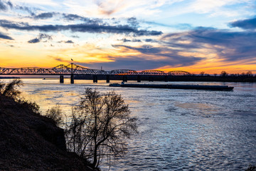 Mississippi River Bridge and towboat with barges at sunset in Vicksburg, MS