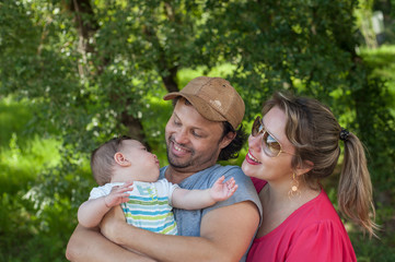 Front view of happy parents playing with their baby in the park.