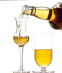 Two goblet in the shape of a tulip with whiskey. Whiskey is pouring from a bottle into a goblet.