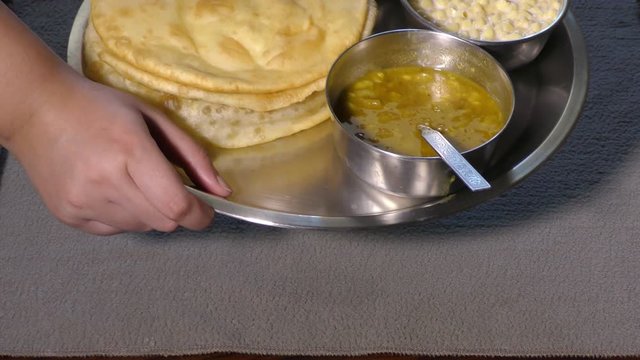 Serving chole bhature to guestes with hands and puting the plate