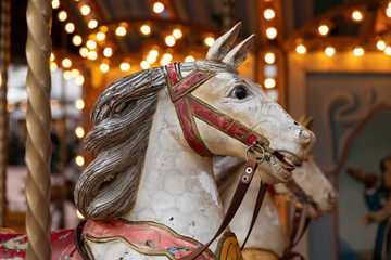 Fototapeta na wymiar Head of an old vintage horse carousel ride in the city center of Eindhoven on the market, an authentic retro merry go round with lights on the background