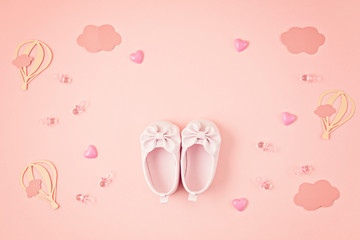 Cute newborn baby girl shoes with festive decoration over pink background. Baby shower, birthday, invitation or greeting card idea