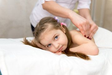 Fototapeta na wymiar woman doing massage to a little girl. Wellness massage for scoliosis