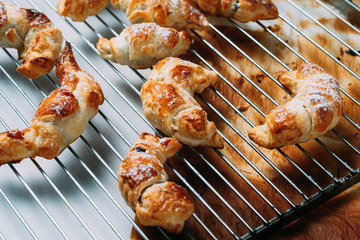 Homemade croissant on oven rack. Wooden bottom and burnt paper of oven