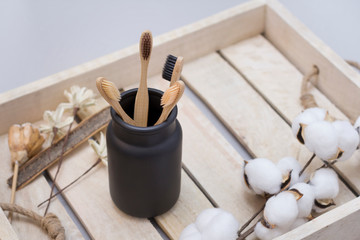 Bathroom essentials. Natural four bamboo toothbrushes in ceramic dish on wooden tray. Lifestyle concept. Zero waste at home