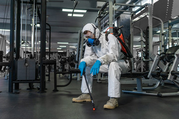 Cleaning and Disinfection in crowded places amid the coronavirus epidemic Gym cleaning and disinfection Infection prevention and control of epidemic. Protective suit and mask and spray bag COVID-19