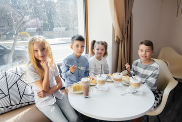A large friendly company of children celebrate the holiday in a cafe with a delicious dessert. The day of the birth