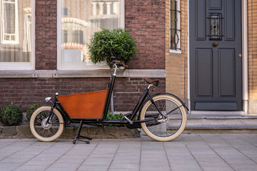 Typical dutch carrier bicycle parked in front of a house. Modern urban parents use these carrier bikes to transport their children or groceries