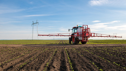 Tractor prepared to spray young corn with pesticides