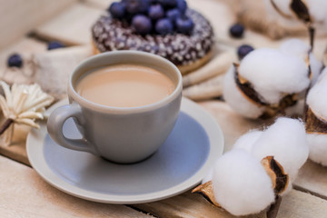 Yammy! Cup of coffee on wooden serving tray and donut with blueberry, morning concept. Selective focus