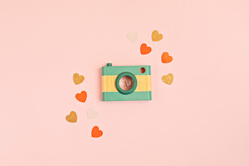 Flat lay with toy wooden camera and hearts over pink background. Social media, posts, likes, followers, online photography classes concept. Top view