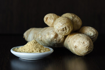 ginger root and powder on dark wooden background. eco food