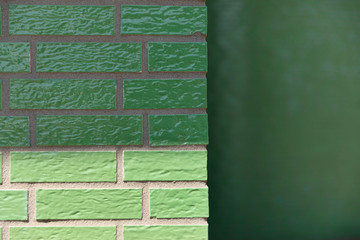 A glazed enamelled green brick wall creating a retro vintage effect on a exterior facade © Lea