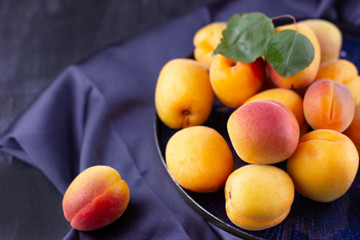 Fresh apricot on dark silk fabric. Ripe sweet berries in droplets of water