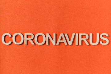 Fototapeta na wymiar coronavirus word with wooden letters on orange background, top view
