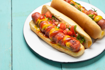 Hot dog with pico de gallo salad on turquoise background