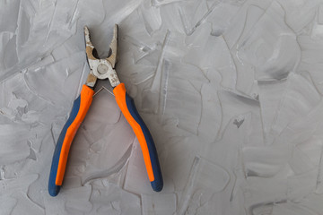 pliers with orange black rubber handles on gray concrete background. 