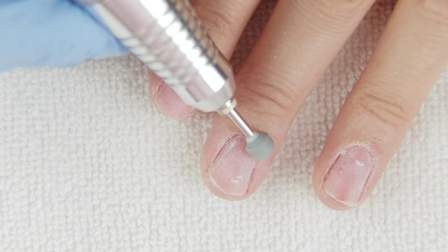 Young woman removes gel shellac polish from nails using manicure machine