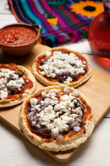 Mexican red sopes with cheese and beans on white background