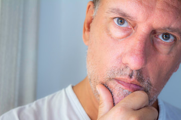 Close up to the face of a white man with a beard half grown while staring. Concept of seriousness and reflection. Middle-aged adult man.