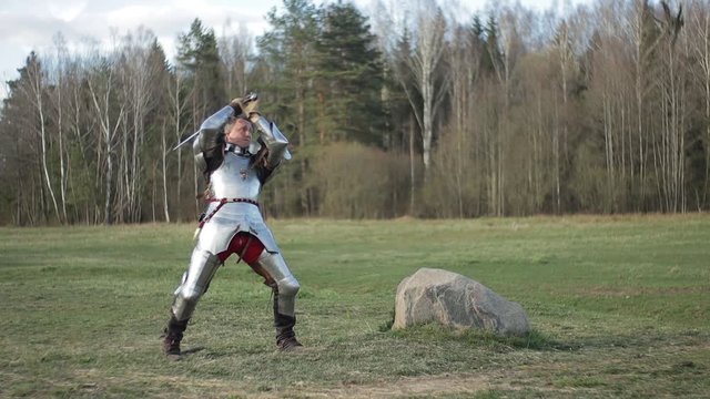 Video footage, a knight on foot in armor and holding a sword in his hands shows combat attacks on the battlefield.
