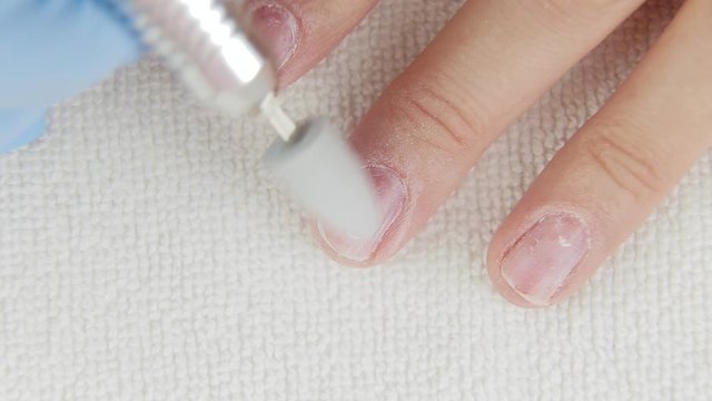 Young woman removes gel shellac polish from nails using manicure machine