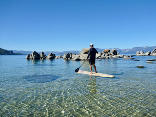 Man paddle boarding on Lake Tahoe on a sunny day